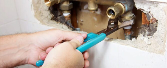 a plumber fixing a dealing pipe that has been causing water damage from the plumbing issue