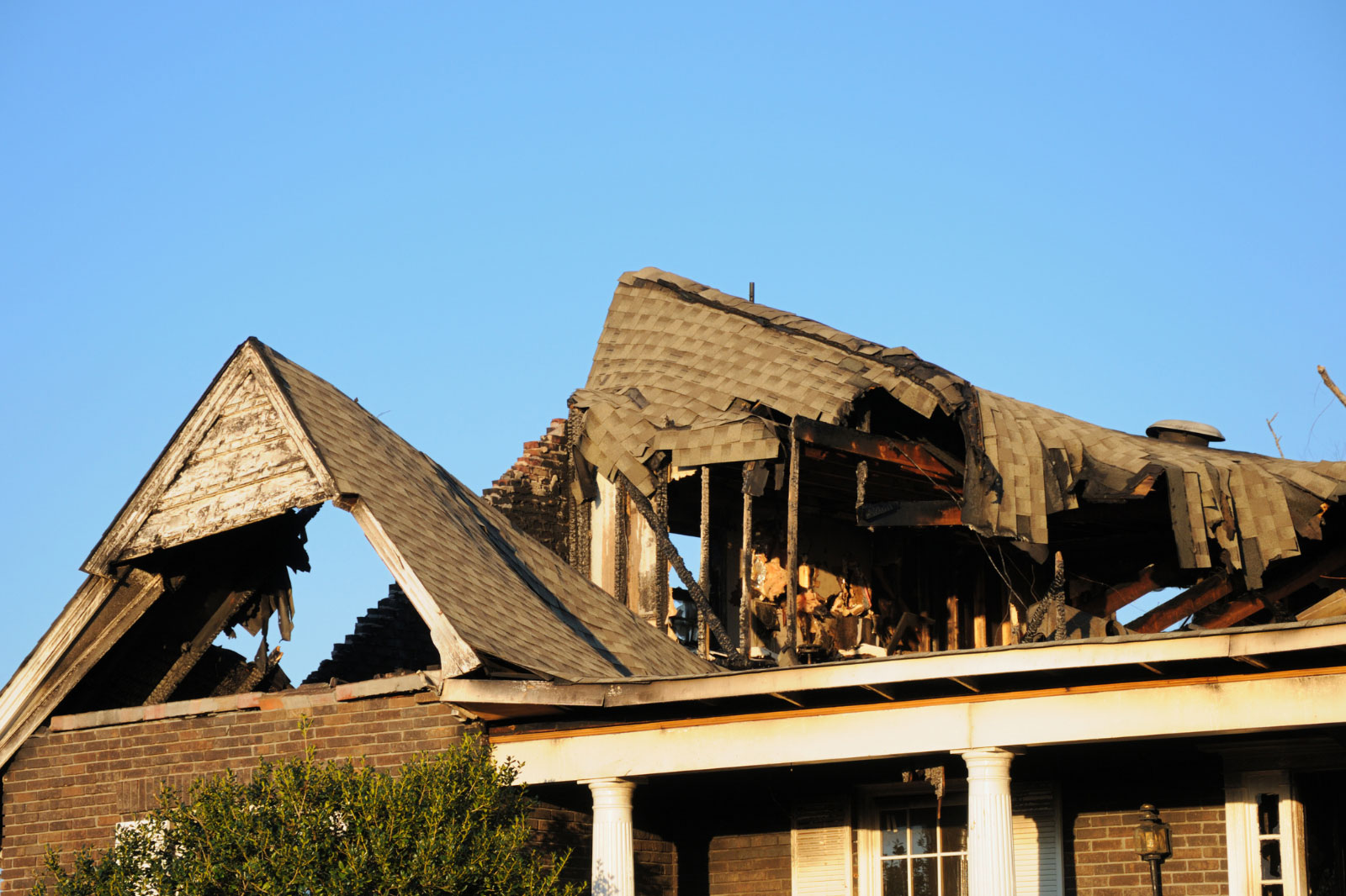 Damaged roof and structure of a house after fire, illustrating severe fire damage and the need for professional restoration services.